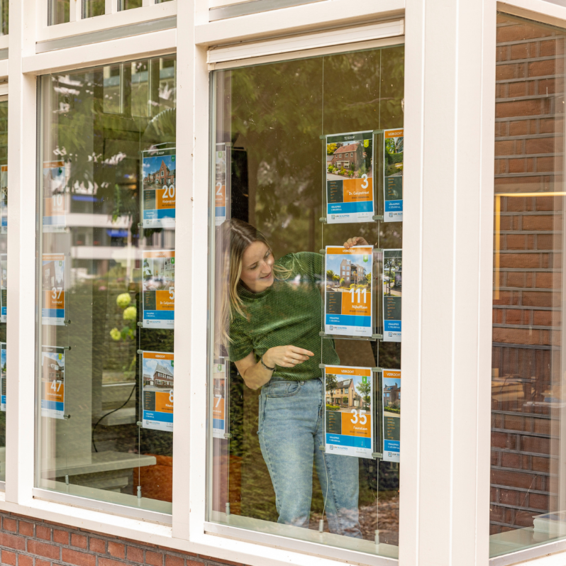 Esmay Bos van Van Schuppen Makelaars hangt woningaanbod in de etalage